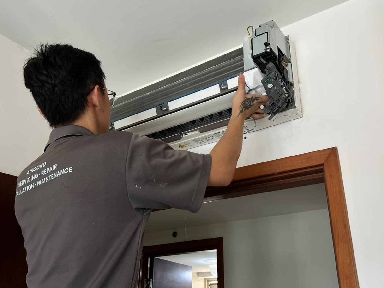 Technician checking the control box of an aircon indoor unit with the cover removed