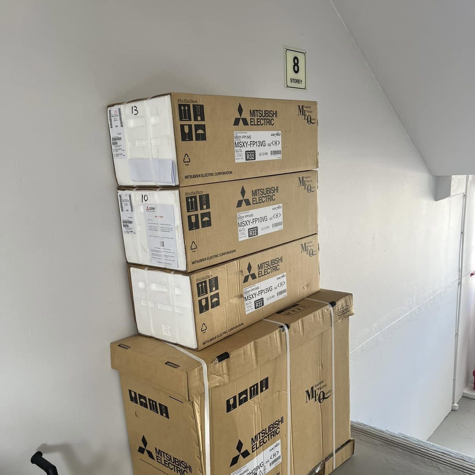 Brand-new Mitsubishi Electric aircon units, still boxed, delivered to an HDB block ready for installation