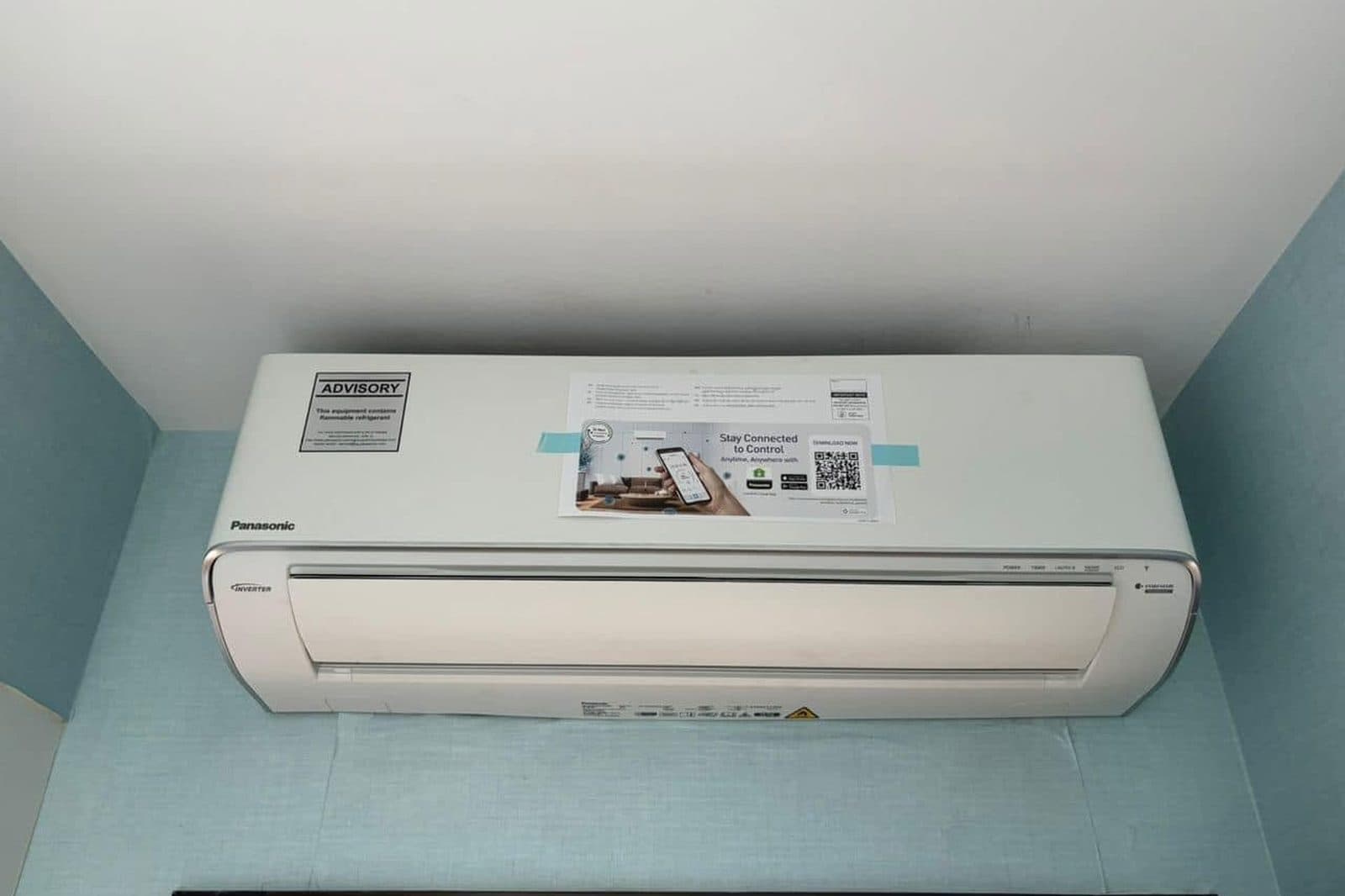 A newly installed Panasonic wall-mounted aircon unit, with the advisory label and protective film still on it