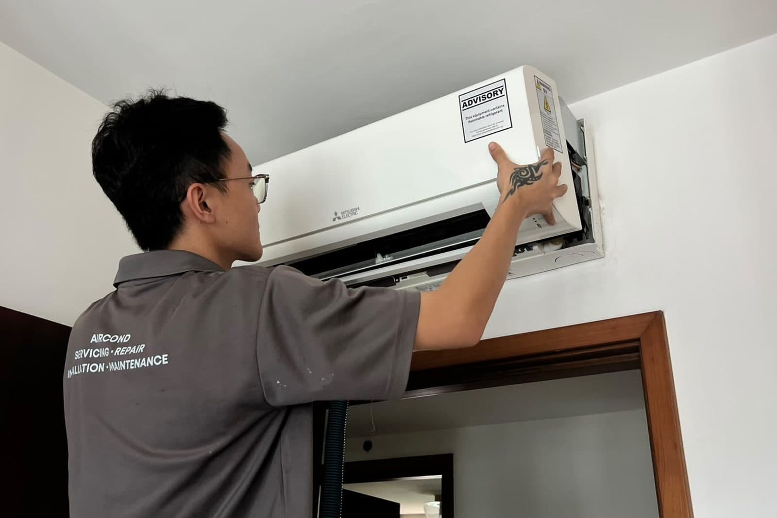 Technician refitting the front cover after finishing an aircon service