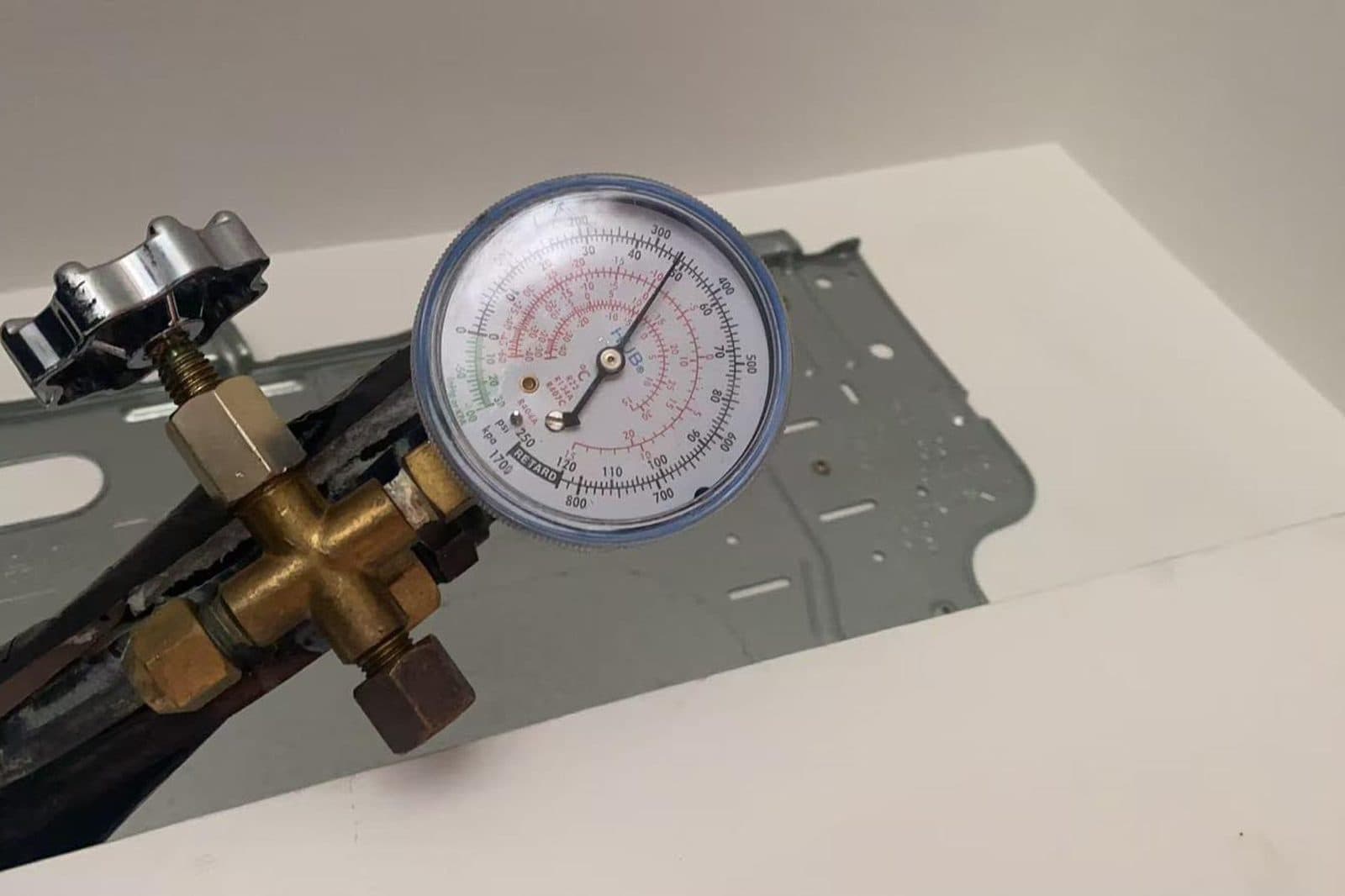 Manifold gauge connected to the refrigerant line while checking an aircon system